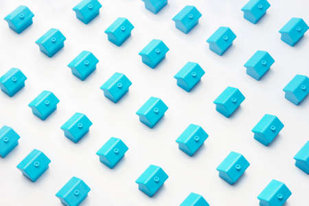 Real estate or property market cottage home. Abstract model village or city district construction new neighborhood pattern of many blue miniature small toy houses stand a rows on white minimal designの写真素材
