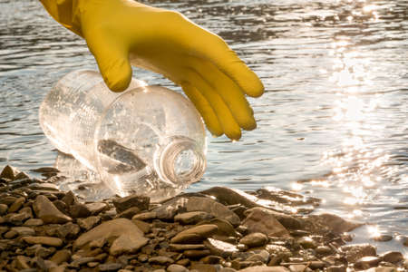 Volunteer cleaning river trash pick up litter picking shore. Collect garbage river. Picking up...