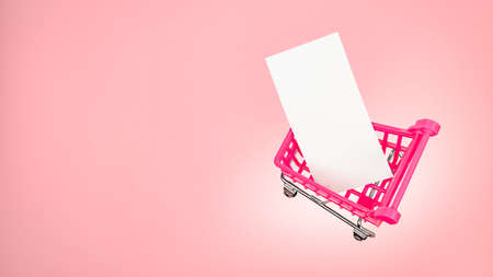 Small shopping cart market trolley with blank paper tag label white blank paper on pink background. Pink sale cart is clear message card blank. Pink shopping trolley cart with blank label card mockupの写真素材