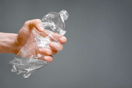 Crumpled bottle pet plastic resize or zero waste plastic hand recycling garbage crush. Raised hands holding crumpled plastic bottle hand squeeze bottle water plastic recycle reuse reduce waste conceptの写真素材