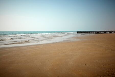 View of a beach with sea and a lighthouse in the background の写真素材