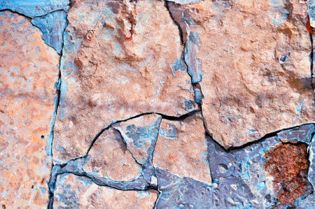 Stone background - closeup of old rough broken pale pink stone with deep turquoise cracks