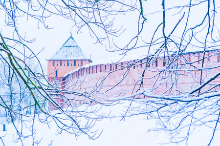 Veliky Novgorod Russia. Vladimir tower of Veliky Novgorod Kremlin fortress, winter cloudy view framed with frosty tree branchesの写真素材