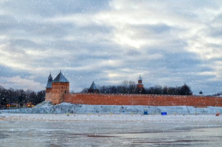 Veliky Novgorod Kremlin fortress, defensive walls and the Volkhov river in Veliky Novgorod, Russia, winter cloudy evening with snowfallの写真素材