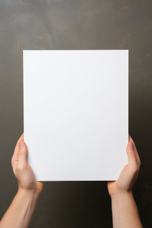 Hands holding blank paper sheet on dark background, top view. Mockup for design.の素材