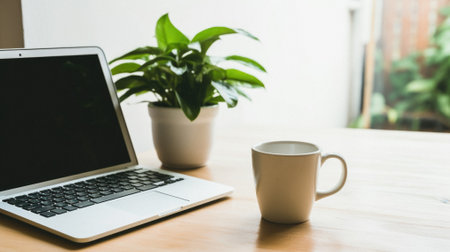 Laptop and coffee cup on wooden table in office, stock photo.の素材