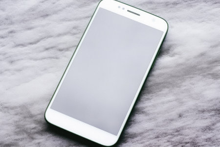 Smartphone with blank screen on white marble background. Copy space.の素材
