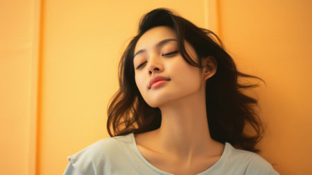 Portrait of a beautiful Asian woman in front of yellow wall.の素材