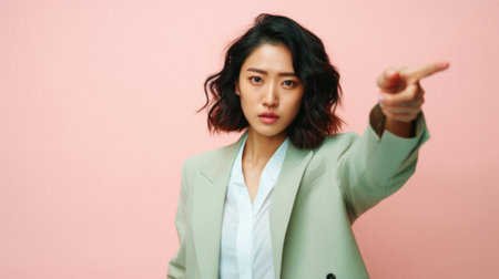 Portrait of young Asian businesswoman pointing at something on pink background.の素材