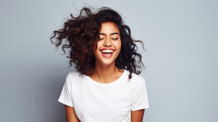 Young happy smiling Indian woman model wearing tshirt looking at camera standing on color background. Face skin care cosmetics makeup, fashion ads. Beauty portrait. White t-shirt mock up template.の素材