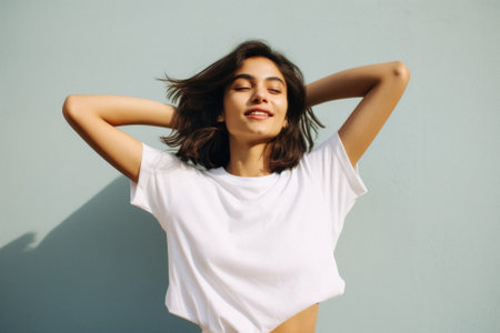 Young happy smiling Latin woman model wearing tshirt standing on color background. Face skin treatment, curly hair care cosmetics makeup, fashion ads. Beauty portrait. White t-shirt mock up template.の素材