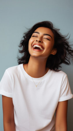 Young happy smiling Indian woman model wearing tshirt looking at camera standing on color background. Face skin care cosmetics makeup, fashion ads. Beauty portrait. White t-shirt mock up template.の素材