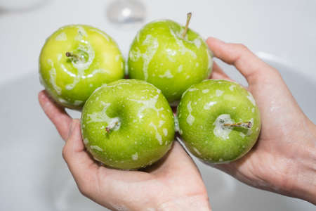 Washing fruit. Girl washes apples. Hands and soapy green apple