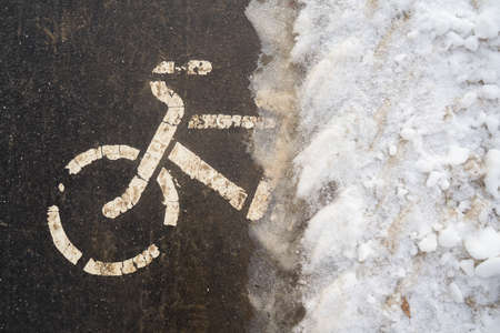 Bicycle path in winter under the snow. The bike season is closed due to ice. Biking in cold weather,...