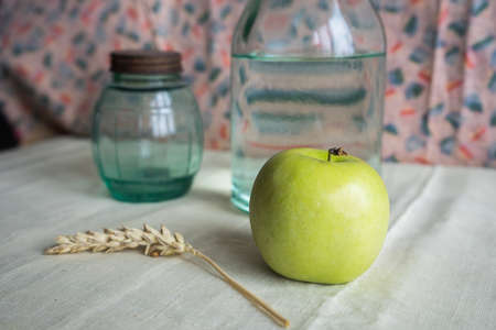 Still life with green apples, water bottle, wheat and can on the table. Apples lie on a background of drapery. High quality photoの写真素材