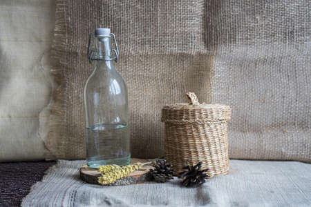 Still life with cones, a glass bottle and wheat on a background of drapery. Artwork for drawing in...