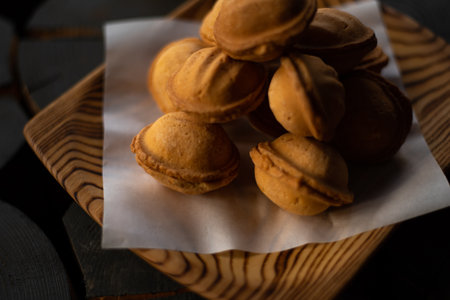 Cakes in the form of nuts from shortbread dough in a wooden plate in dark colorsの写真素材