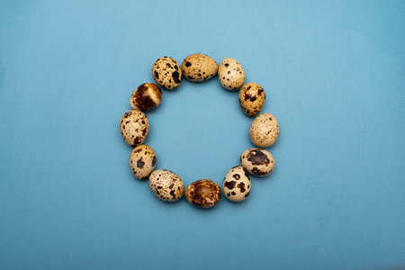 A circle of quail eggs on a blue background.