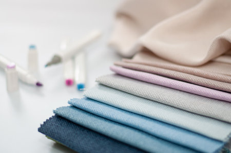 Samples of textured fabric for curtains in pink and blue colors and markers on a white background.