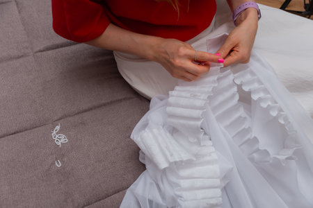 Women's hands in a close angle put hooks on the ribbon on the curtains. White curtains and tulle.