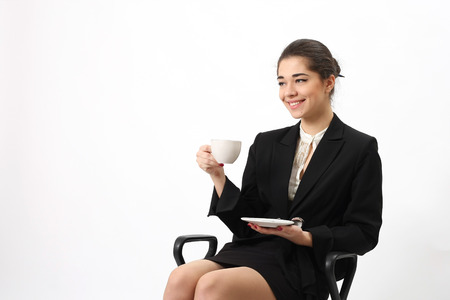 Business woman portrait with cup sitting in the chair of an office, isolated.の写真素材