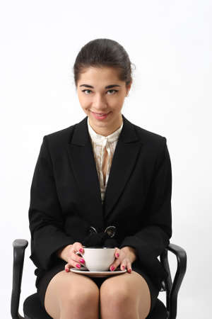 Business woman portrait with cup sitting in the chair of an office, isolated.の写真素材