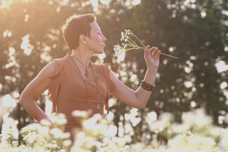 beautiful girl outdoors smelling wild daisiesの写真素材