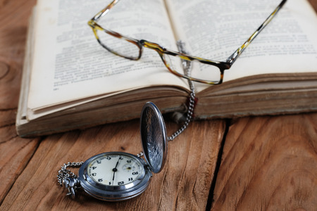 old book vintage watches glasses on wooden boardの写真素材