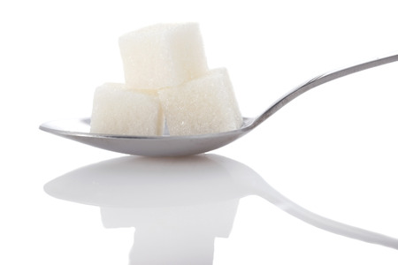 cubes of white sugar in a metal spoon closeup on white background isolateの写真素材