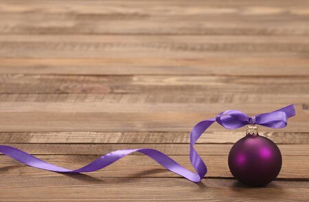 Christmas Toy purple ball with ribbon on a background of boardsの写真素材