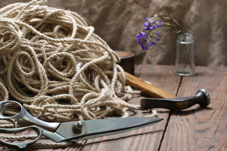 scissors matted jute rope and a hammer on a background of wooden planksの写真素材