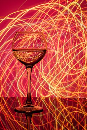 a glass of white wine on a blurred colored background closeupの写真素材