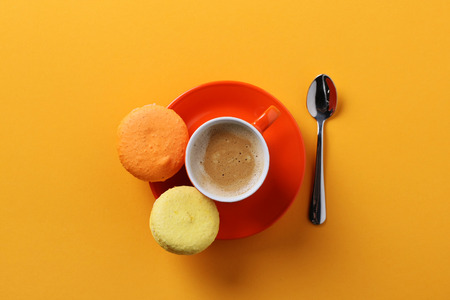 orange cup of coffee with macaroons on a yellow background. from aboveの写真素材
