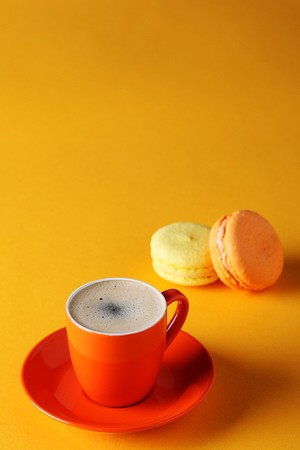 orange cup of coffee with macaroons on a yellow background close-upの写真素材