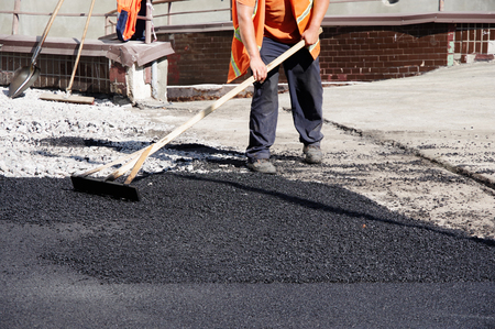 road workers level the hot asphalt by handの写真素材