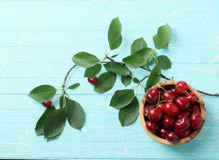 ripe cherries in a wooden bowl on the background of wooden painted boards