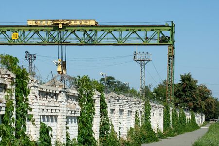 gantry crane behind a brick fence with barbed wireの写真素材