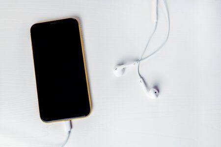 12.08.2019 Ukraine: yellow iphone xr and headphone on isolated backgroundのeditorial素材