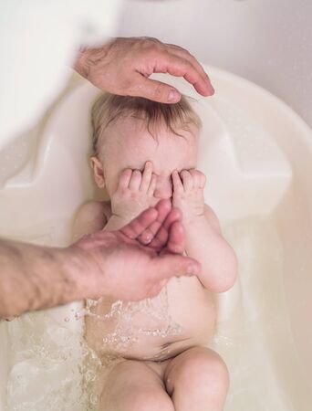 Little baby in a bathroom are washing with his fatherの写真素材