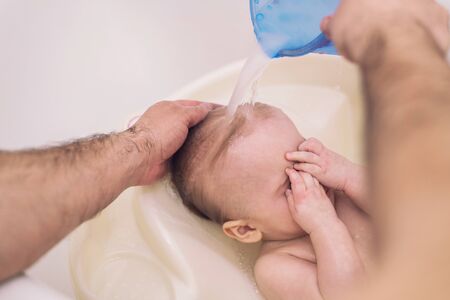 Little baby in a bathroom are washing with his father