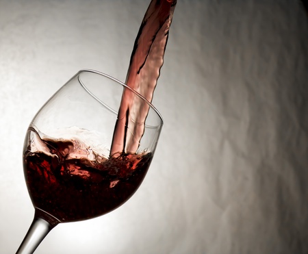 Wine smoothly poured into glass on grayの写真素材