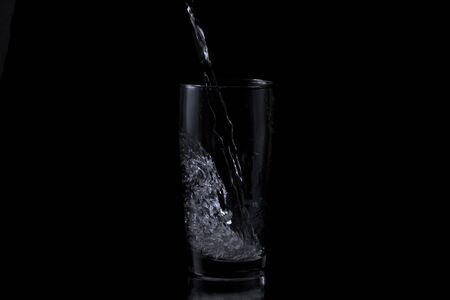 First drops of water hitting and splaishing in a glassの写真素材