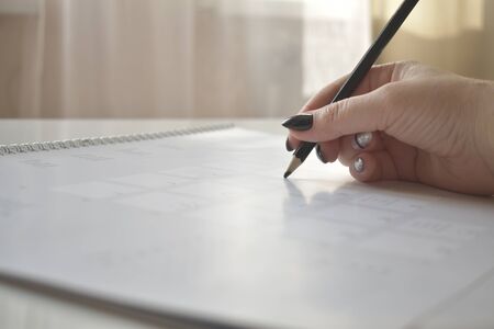 Calendar and women's hand with pen, phone, workspace, business plan, curriculumの写真素材
