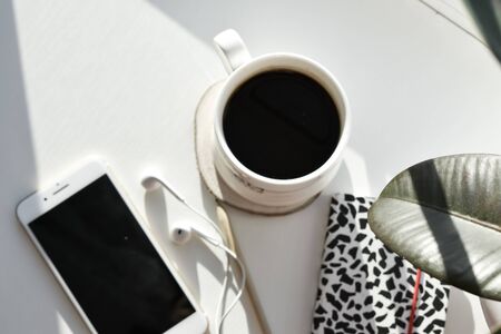 phone with headphones and a notebook with animal print and a black envelope is open and the envelope...