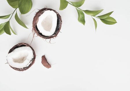 Tropical leaves and fresh coconuts, coconut frame with half and leaves on a white background with...