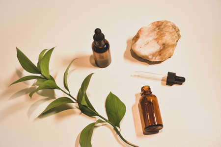Natural cosmetic oils on a natural beige background with the decor of their stones and plant leaves....