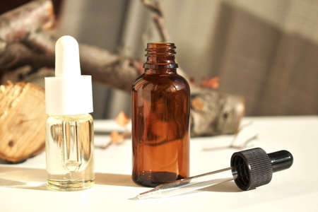 Cosmetic fragrance oils in bottles with pipette on the background of natural wood and pastel colors....