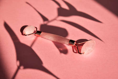 Massage with a quartz roller for the face with pink natural jade.