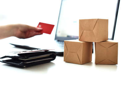 Online store. Purchase online. Paper boxes and credit cards in hand near the laptop. An online shopping service that offers home delivery.の写真素材