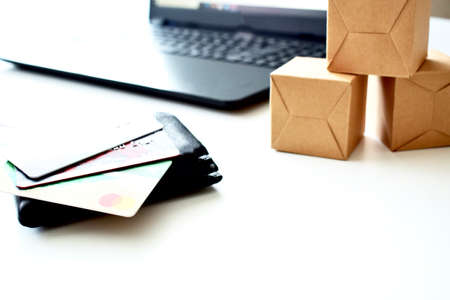 Online store. Purchase online. Paper boxes and credit cards in hand near the laptop. An online...